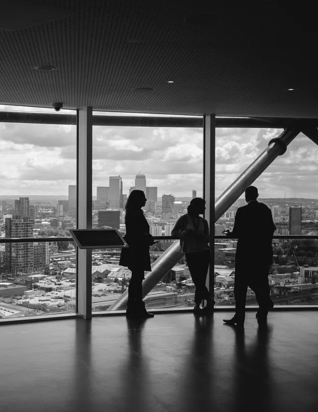 Three colleagues by the window of a skyline office